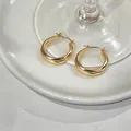 Detailed macro view of elegant minimalist gold twisted hoop earrings on white dish - Twisted Cross Style (HE33374) / Gold