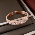 Detalle de un elegante brazalete abierto de varias capas en oro rosa con cristales - Dorado