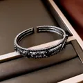 Vista detallada de un brazalete abierto multicapa con diamantes negros en bandeja terciopelo - Gris metalizado