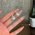 Detailed close-up view of elegant pearl earrings with zircon accents on silver needles. - Silver Earring Post-White / Silver