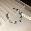Detail shot of sparkling zircon bracelet with emerald green stones in grey tray - Silver-Green