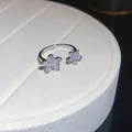 Close-up detail of a silver open ring featuring two sparkling zircon flower charms on a tray - Double Flower Ring (HR3291) / Silver