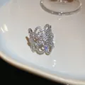 Dettaglio di un anello a fiore traforato color argento con pietre di zircone scintillanti - Fiore Traforato / Argento