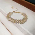 Detail showing a handmade gold hollow lattice bracelet with clear crystal beads - White Beads / Gold