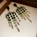 Primo piano di eleganti orecchini a nappa con cristalli verdi in una scatola portagioie. - Stile Nappa Quadrata con Perno in Argento / Verde