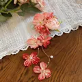 Vista dettagliata di un elegante fermaglio con fiori di stoffa rosa, nappe di perle e catene. - Fermagli per capelli a becco d'anatra / 1 Pezzo / Rosa