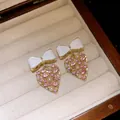 Nahaufnahme von Vintage-Ohrringen mit Schleife und Herz, rosa Strass und Perlen in einer Box - Silberstift Bogen Herz Stil / Gold-Weiß-Rosa