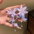 Detailed macro view of elegant purple fabric flower tassel earrings with pearls and zircons - Pink