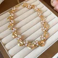 Elegant gold-tone bow necklace with white pearls and crystals displayed in a velvet box - Necklace / Gold