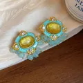 Close-up detail of vintage gold oval resin earrings with blue beads and rhinestones - Gold-Yellow