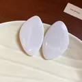 Vue macro détaillée d'élégantes boucles d'oreilles en résine blanche en forme de feuille - Blanc