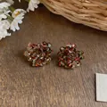 Close-up of vintage glass beaded cluster flower earrings on a rustic wooden table - Light Red