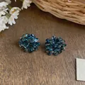 Close-up macro of deep blue glass beaded flower cluster earrings on rustic wood table - Blue