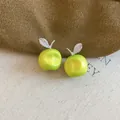 Close-up of green apple earrings with sparkling leaf detail on linen background. - Green Apple Style