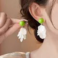 Dettaglio ravvicinato di orecchini a nappa con petali in acrilico bianco e perline verdi. - Stile Fiore con Nappina (HE34316) / Ago d'argento / Verde e Bianco