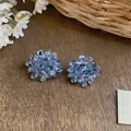 Detailed macro shot of blue glass beaded flower earrings placed on a rustic wooden texture - Lavender