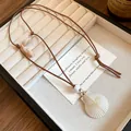 Detailed view of beach-themed shell necklace with scallop pendant on brown cord cord. - Scallop / Coffee