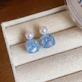 Detailed macro shot of square blue glass and pearl stud earrings in jewelry box - Square Pearl Design / Blue