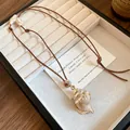 Detailed macro view of a beach-style seashell pendant necklace on a cream jewelry tray - Conch / Coffee