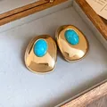 Close-up detail of vintage gold oval stud earrings with elegant turquoise resin stone inlay - Gold
