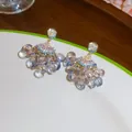 Gros plan de boucles d'oreilles pompons en zircon en forme d'éventail avec perles bleues. - Or Bleu Violet
