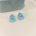 Detailed macro view of light blue enamel waterdrop earrings featuring sparkling pear-cut zircon - Blue