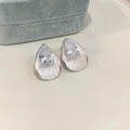 Elegant pear-shaped zircon stud earrings with white enamel finish on a neutral background. - White