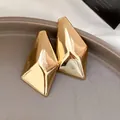 Detaillierte Nahaufnahme goldener unregelmäßiger geometrischer Ohrstecker mit Metallglanz - Unregelmäßiger Geometrischer Stil / Gold