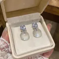 Close-up of French style silver needle earrings with clear resin round studs and diamonds - Round Resin Style / Silver