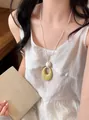 Elegant long necklace featuring a textured yellowish-green oval pendant worn by a model - Yellow