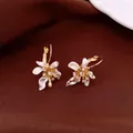 Gros plan d'élégantes boucles d'oreilles fleurs vintage avec émail blanc et zircons - Clip d'oreille-Or-Blanc