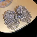 Close-up view of elegant silver needle earrings with shimmering rhinestone tassels - Silver
