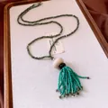Detailed macro view of a retro ethnic style beaded necklace featuring turquoise glass tassels - Green and Blue