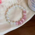 Close-up of a sweet pearl bracelet with pink cat's eye beads on elegant silk fabric - White-Pink