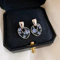 Primo piano di orecchini vintage in argento con strass blu in una scatola di velluto - Ago d'argento / Argento-Blu