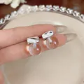 Close-up detail of minimalist silver stud earrings with clear resin spheres - Silver Earring Post Round Style / Silver-White