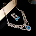 Vue rapprochée d'un ensemble collier et boucles d'oreilles en cristal avec gouttes bleues - Argent-Bleu