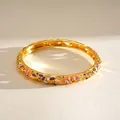 Detailansicht eines vergoldeten Armreifs mit Emailleblumen und funkelnden Strasssteinen - Violette/Orangefarbene Blume (HB6168) / Gold