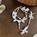 Detailed view of a French sweet style pearl necklace with white lace bow accents - White