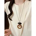 Detail of a bohemian woven flower pendant necklace worn with a cream textured top. - Flower Ring Woven Style (HN12225) / Brown