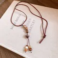 Gros plan d'un pendentif de collier en graines de Bodhi tressé à la main, style ethnique rétro - Style Graine de Bodhi / Café Or