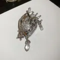 Macro detail of silver anatomical heart brooch with sparkling crystals and drop pendant - Anatomical Heart Style / Silver