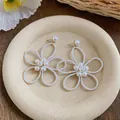 Primo piano di eleganti orecchini a bottone a forma di fiore di perle su vassoio beige - Forma di Fiore (HE33340) / Bianco