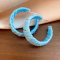 Primo piano di orecchini a cerchio a C avvolti in chiffon azzurro con aghi d'argento - Stile a Forma di C con Perno in Argento / Blu