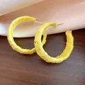 Dettaglio ravvicinato di orecchini a cerchio a C avvolti in chiffon giallo strutturato. - Stile a Forma di C con Perno in Argento / Giallo