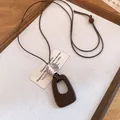 Detailed close-up of a vintage resin and wooden bead pendant necklace on a rustic tray. - Geometric Hollow Square (Style 6)
