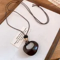 Macro view of a retro resin ring pendant necklace with wood beads and brown wax cord. - Amber Pattern Irregular Ring (Style 2)