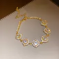 Gros plan d'un luxueux bracelet en or orné de zircons blancs très étincelants. - Style Fleur / Or-Transparent