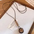 Close-up of vintage resin ring pendant necklace with leather cord and wooden beads - Carved Tube (Style 5)