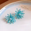 Detailweergave van blauwe kralenbloem oorknopjes met een centraal parelaccent - Stud oorbellen / Blauw